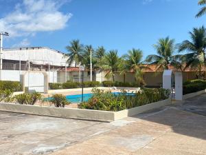 a swimming pool with palm trees and a building at Apto Salinas in Salinópolis