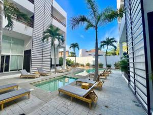a swimming pool with chaise lounge chairs and palm trees at Elegant Coastal Studio in Bucerías