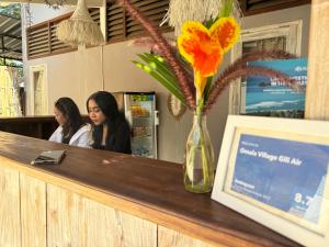 two women sitting at a counter with a vase of flowers at Omala Village Gili Air in Gili Air