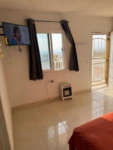 a living room with a tv and a bed and window at Granja Margarita in Tequisquiapan