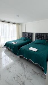 VillamaríaHospedaje Los Termales的一间设有两张绿色床的卧室和大理石地板
