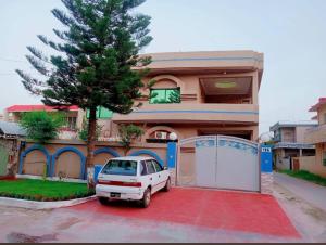 Un coche blanco aparcado delante de una casa en Orion International Guest House, en Islamabad