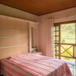 a bedroom with a large bed and a large window at Chalés Rota das Cachoeiras in Urupema