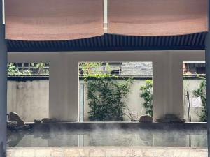 a large window in a building with a courtyard at Mount Emei Heyuan Serene Residence Hot Spring Hotel in Emeishan City