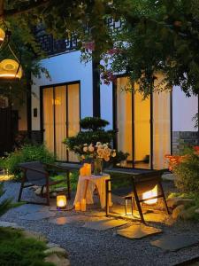 a patio with a table and chairs and a building at Mount Emei Heyuan Serene Residence Hot Spring Hotel in Emeishan City