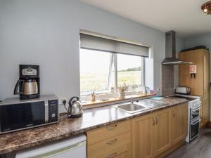 a kitchen with a microwave and a sink and a window at Budle Bay Cottage in Bamburgh +6 photos
