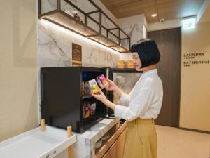 台北市にあるRoyal Rose Hotel Zhongshanの女が冷蔵庫に食べ物を入れている