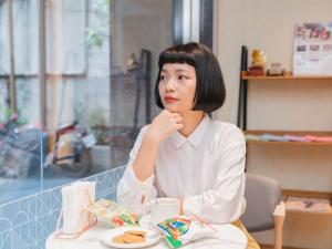 台北市にあるRoyal Rose Hotel Zhongshanの食べ物の皿を持ってテーブルに座っている女性