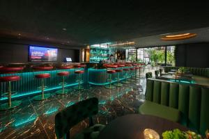 a bar with red stools and a tv in the background at MAY DE VILLE Crown Hotel in Hanoi