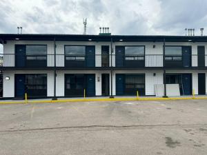 un edificio blanco con puertas azules y aparcamiento en Cozy Motel Studio with kitchenette - 8, en Edmonton