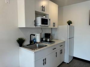 Una cocina blanca con fregadero y refrigerador. en Cozy Motel Studio with kitchenette - 8, en Edmonton