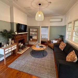 un salon avec un canapé et une table dans l'établissement Fitzroy Olive Cottage, à Dubbo