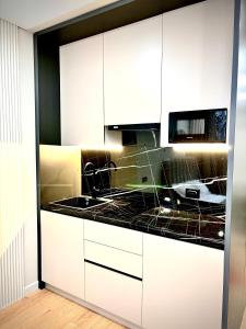 a kitchen with white cabinets and a black counter top at 1 комнатная, уютная квартира в новом ЖК in Kostanay