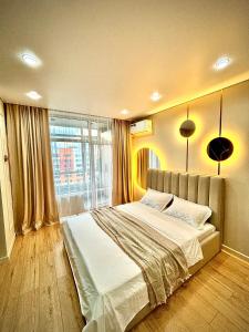 a bedroom with a large bed and a large window at 1 комнатная, уютная квартира в новом ЖК in Kostanay