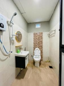 a bathroom with a toilet and a sink at Casaria Inn Paka in Paka