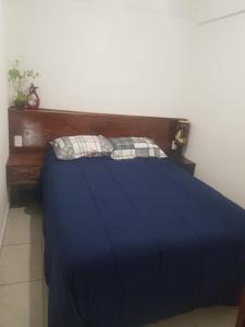 - une chambre avec un lit bleu et une tête de lit en bois dans l'établissement Departamento los Pinos, à Zurumútaro