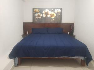 - un lit avec une couette bleue dans une chambre dans l'établissement Departamento los Pinos, à Zurumútaro