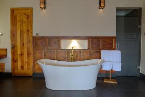 a bath tub in a bathroom with a wooden wall at Willing Resort, Trongsa in Kagha +72 photos
