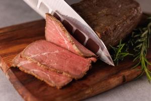 a cutting board with meat and a knife on it at WeBase TAKAMATSU in Takamatsu