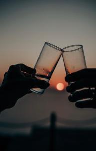 a person holding two glasses of wine with the sunset in the background at SECRET HILL in Athani