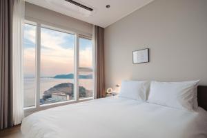 a bedroom with a large white bed and a large window at Le Collective Haeundae Paragraf in Busan