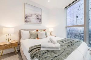 a bedroom with a white bed with a large window at Vibrant & Lively Condo with Stunning City Views in Melbourne +23 photos