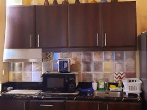 a kitchen with brown cabinets and a microwave at Cozy Corner Haven near Venice Grand Canal Mall in Manila