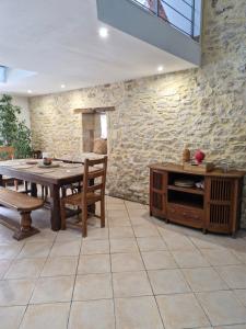 a dining room with a table and a stone wall at Demeure en pierre avec piscine privée in Étauliers