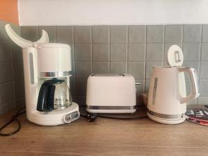 3 cafetières et un grille-pain sur un comptoir de cuisine dans l'établissement Maison 2 chambres- grand jardin-WIFI - au cœur du village AUBETERRE -visites- conciergerie J&N, à Aubeterre-sur-Dronne