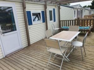 a patio with a table and chairs on a deck at Ecuries Leseigneur - Camping Insolites in Bolleville