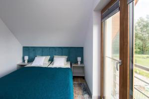 a bedroom with a blue bed and a window at Dom Gościnny Ogrodowa in Wiślinka