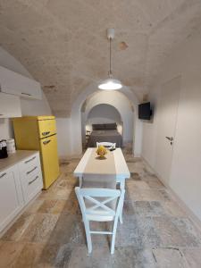 La cuisine est équipée d'une table blanche et d'un réfrigérateur jaune. dans l'établissement Corso Perrini, 68, à Fasano