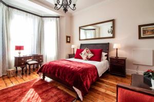a bedroom with a bed with red sheets and a mirror at Carmichael House Boutique Hotel in Cape Town