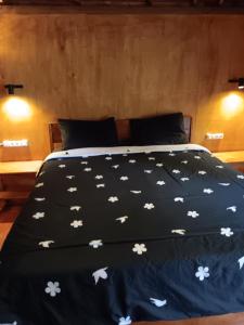 a bed with a black comforter with flowers on it at Tetebatu Sunrise Homestay in Tetebatu