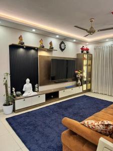 a living room with a tv and a person sitting on a couch at Elite 3BHK- 19th Floor Only for Family in Bengaluru