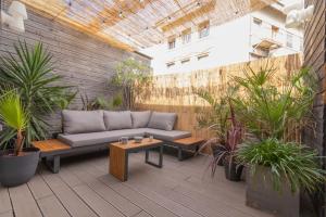 a patio with a couch and a table and plants at AfroBoHome, Expérience Atypique, clim, 2 à 6 personnes, Proche centre Nîmes, Garage clos in Nîmes