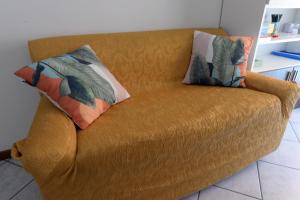 an orange couch with two pillows on it at Appartamento Climatizzato con Piscina Ca' Aurelia in Lido di Savio