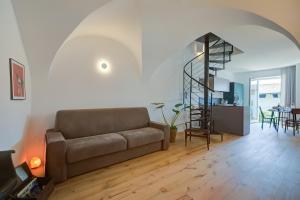 un soggiorno con divano e una scala a chiocciola di Al Mandorlo Family & Bike Friendly - Happy Rentals ad Arco