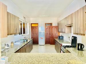 a large kitchen with wooden cabinets and a refrigerator at Elna's Nyali - Work & Unwind - Pool, Sea Views, AC & Fast Wi-Fi in Mombasa