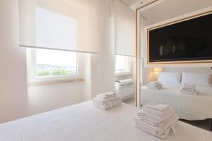 una camera da letto bianca con due letti e uno specchio di La Finestra Sul Mare Central Apartment Vista mare ad Anzio