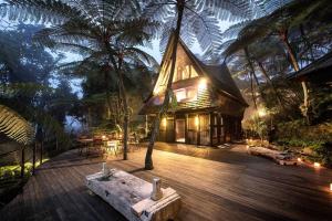 a wooden deck with a house in the jungle at Batak Legacy, A Jungle Hideaway in Tabanan