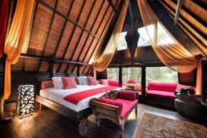 a bedroom with a bed in a room with windows at Batak Legacy, A Jungle Hideaway in Tabanan