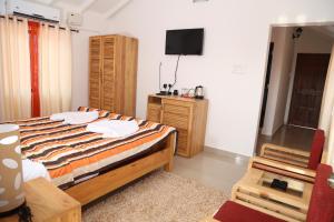 a bedroom with a bed and a tv on the wall at Villa Baywalk Goa - 200 meters from Morjim Beach in Morjim