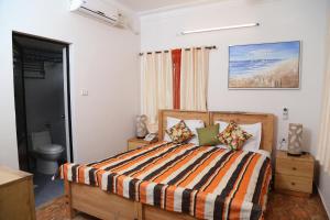a bedroom with a bed with a striped comforter at Villa Baywalk Goa - 200 meters from Morjim Beach in Morjim