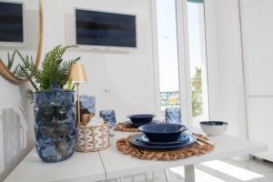 un tavolo bianco con piatti blu e un vaso di La Finestra Sul Mare Central Apartment Vista mare ad Anzio