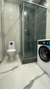 a bathroom with a washing machine and a toilet at Уютная 1-ком кв в Жк Альтаир мкр Батыс-2 in Aktobe