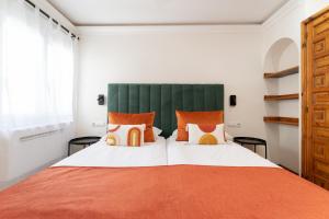 1 dormitorio con 1 cama grande con almohadas de color naranja y blanco en Alsol El Chaparral, en Playa del Inglés 36 fotos más