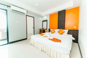 a bedroom with a large bed with an orange wall at Saiyuan Residence Phuket in Rawai Beach