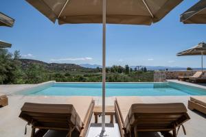 a villa with a swimming pool and an umbrella at Istorima Guesthouse in Gythio