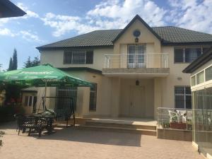 a house with a table and a green umbrella at Buzovna Villa in Baku